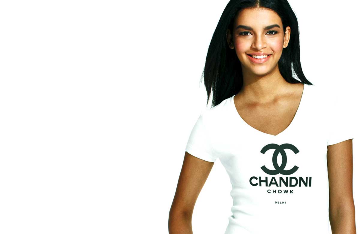South Asian model wearing Gildan SoftStyle V Neck tshirt with black silkscreened image on front that says Chandhni Chowk. Tshirt is designed by Brown Man Clothing Co.